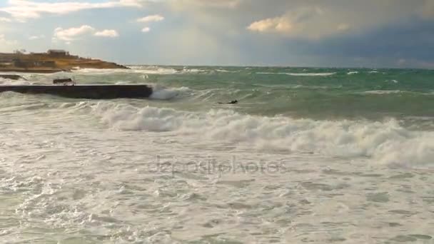 Sur le rivage viennent les vagues de tempête qui essaient de monter un doigt 