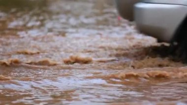 Arabayı bir su birikintisi geçer. Ağır çekim.