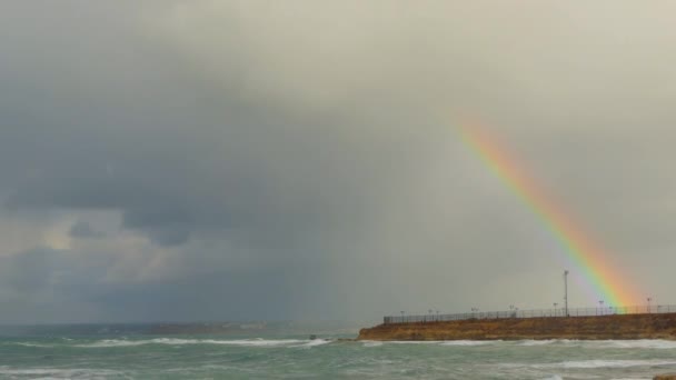 Arco iris después de la tormenta se eleva desde el mismo suelo sobre el paseo marítimo de la ciudad — Vídeo de stock