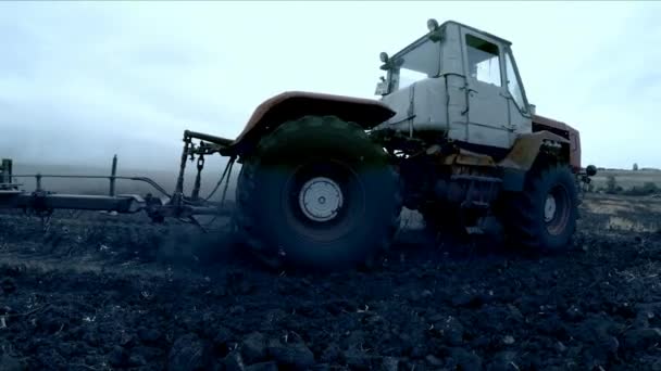 Traktor med plog släpvagn plöjning fältet efter solnedgången — Stockvideo