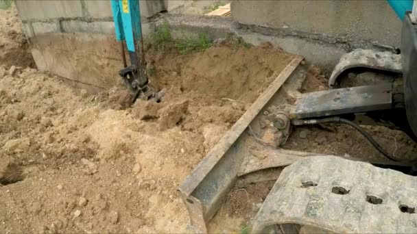 Excavator digs a trench next to the building. Slow motion. — Stock Video