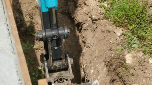 Excavator digs the ground next to the wall — Stock Footage Excavator digs the ground next to the wall Royalty Free Stock Footage