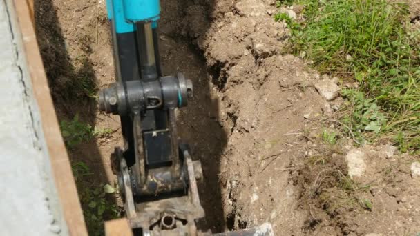 Bagger gräbt den Boden neben der Mauer aus — Stockvideo