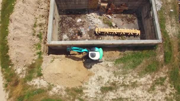 Excavadora azul cava la tierra con un edificio. aves vista del ojo . — Vídeos de Stock