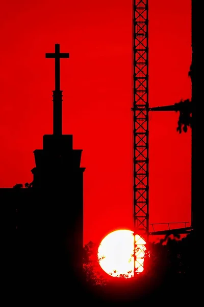 日没のシルエット建築クロス タワー クレーン スローンの教会の屋根の上 — ストック写真