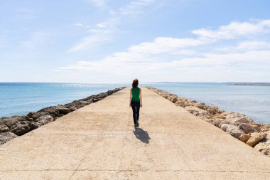 İskelenin sonuna doğru yürüyen bir kadın.