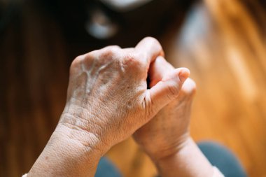 Yaşlı kadın elleri bastonun üzerinde dinleniyor.