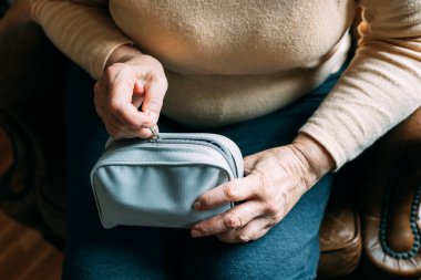 Yaşlı kadın tansiyonunu ölçmeye hazırlanıyor. Bir sfenometre ile.