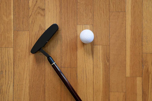 Golf sopası ve golf topu parke zeminde.