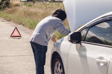 Yolda kırık araba yakınında Acil dur işareti ve sürücü. 