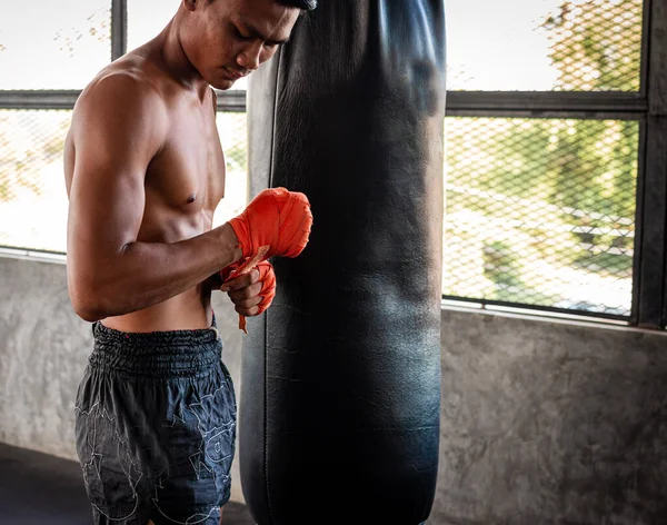 Man boxer wrapping his hand in boxing arena sport.