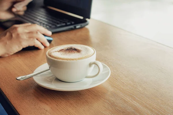 Freelancer working in cafe on a wooden counter bar with coffee mugs and laptop.