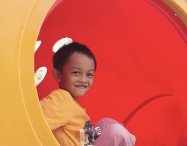 Gündüz vakti renkli bir oyun parkındaki çocukların mutlu gülümsemeleri..