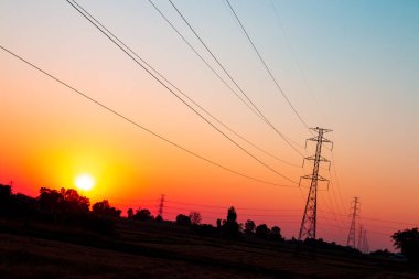 Gün batımının güzel arka planında yüksek voltajlı güç iletim hattı