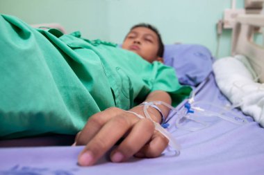 Asyalı bir çocuk hastane yatağında bir hastayı tedavi ediyor..