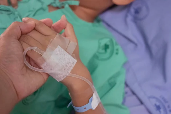 Hastanedeki hastaları cesaretlendirmek için çocuğun elini tutan baba..