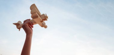 Mutlu çocuklar günbatımında arka planda tahta bir oyuncak uçak oynuyorlar.