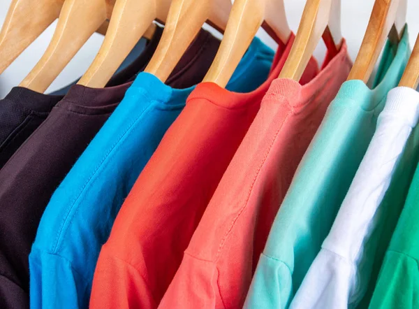 Giysi rafındaki moda tişörtü - Dolaptaki ahşap askılarda parlak renkli dolabın kapatılması