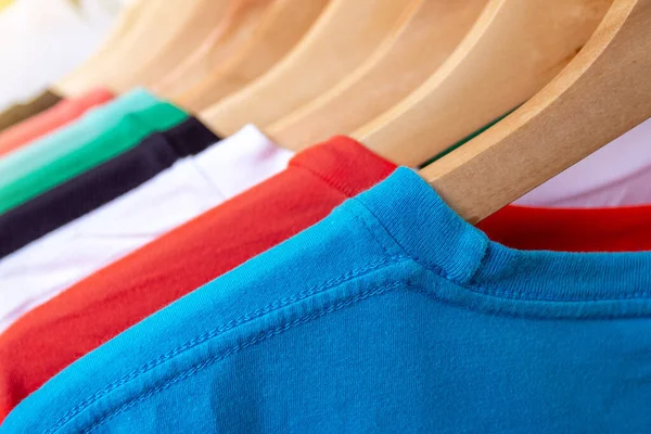 Fashion T-shirt on clothing rack - Closeup of bright colorful closet on wooden hangers in store closet