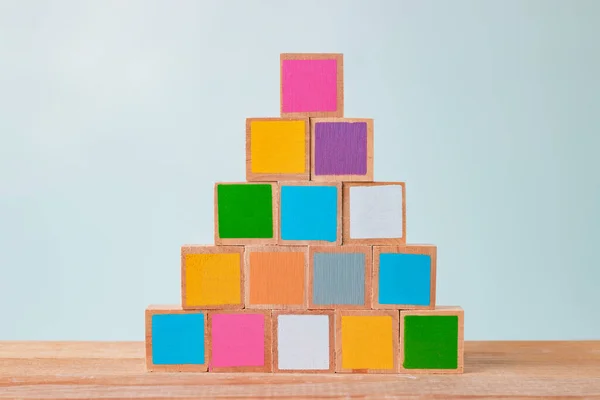 Wooden blocks of many colors arranged on a wooden table, Pastel tones