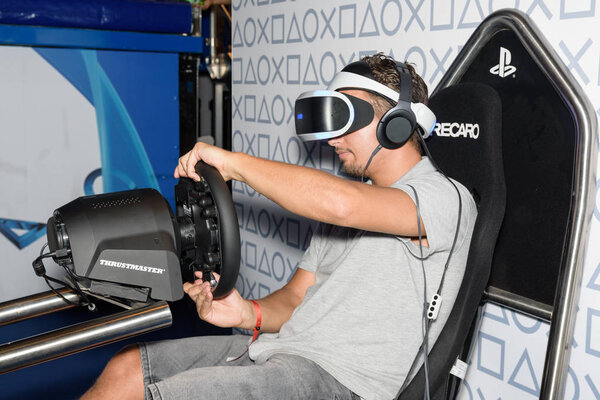A trade fair visitor is playing a racing game with vr headeset