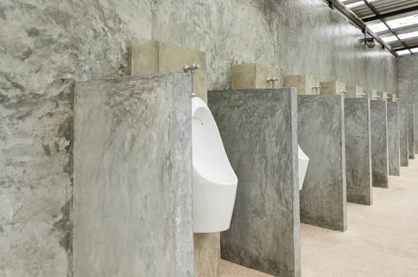 Pisuar białych mężczyzn w publicznej toalecie mężczyzn z betonu ściany Loft St — Zdjęcie stockowe