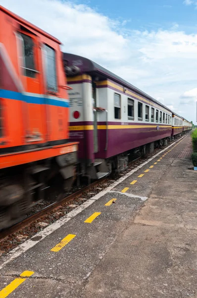 A train is passing a rural station in Thailand