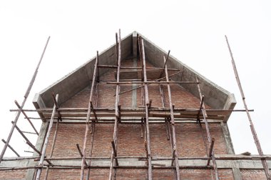 İnşaat evinin altında kırmızı tuğla duvar ve beton yapı var.