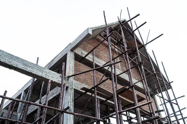 İnşaat evinin altında kırmızı tuğla duvar ve beton yapı var.