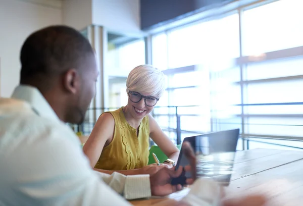 Two creative millenial small business owners working on social media strategy using a digital tablet while sitting at desk — Stock Photo, Image