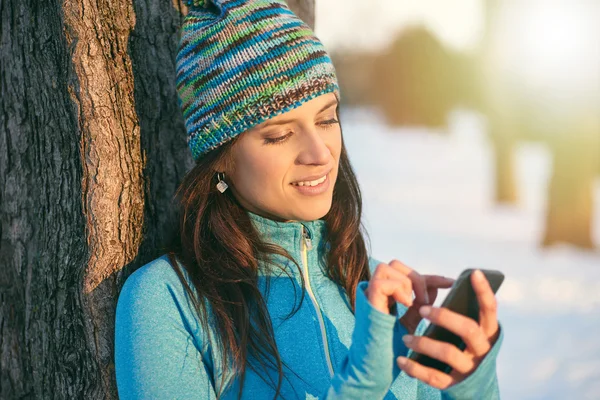 Attractive mixed race woman using a mobile phone in the park at — Stock Photo, Image