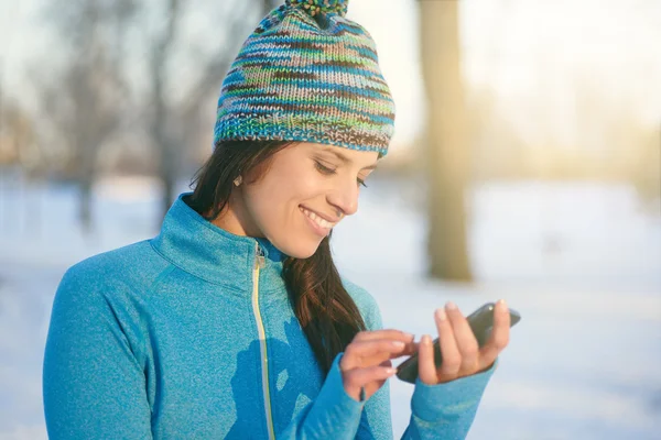 Attractive mixed race woman using a mobile phone in the park at — Stock Photo, Image