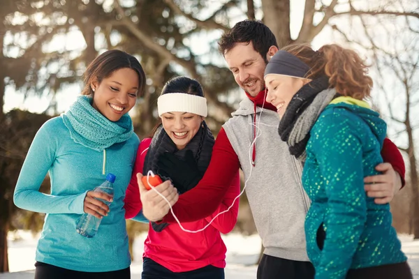 Group of friends listening to music in the snow in winter — Stock Photo, Image