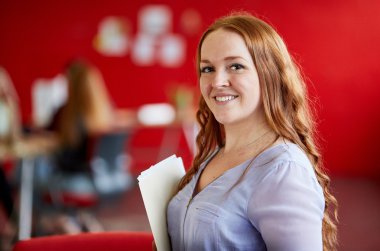 Kendine güvenen kadın tasarımcı çalışma ve bir klasör içinde kırmızı yaratıcı ofis belgeleri gözden geçirme