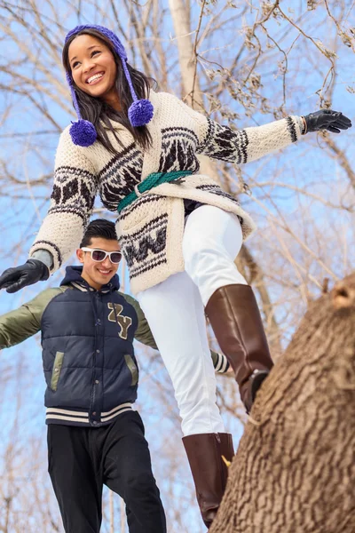 Joven pareja diversa caminando en un tronco en la nieve en invierno — Foto de Stock