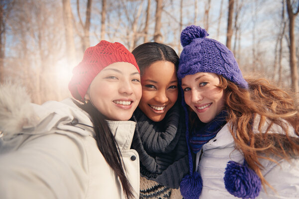 Group of girl friends enjoying taking selfies in the snow in winter