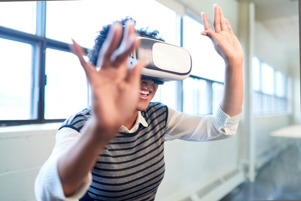 Cool millennial black woman exploring virtual reality glasses in an open-concept space Stock Image