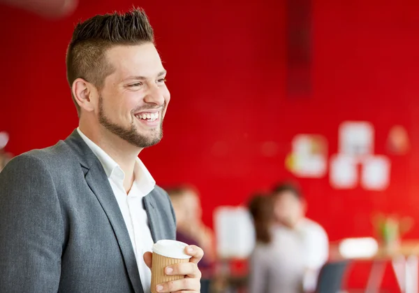 Concepteur masculin confiant prenant un café au travail dans un espace de bureau créatif rouge — Photo