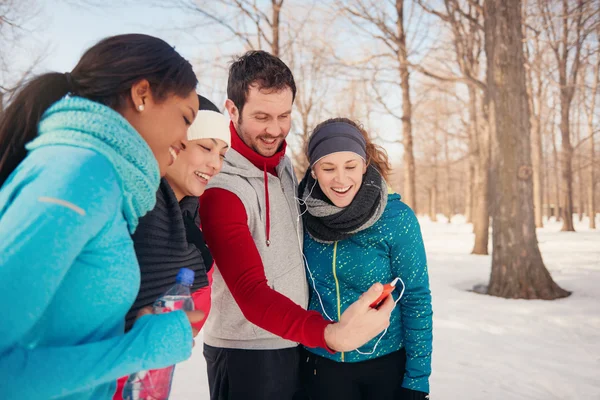 Group of friends listening to music in the snow in winter — Stock Photo, Image