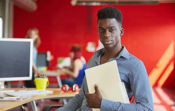 Fiducioso designer di sesso maschile che lavora e rivede i documenti all'interno di una cartella in uno spazio ufficio creativo rosso — Foto Stock