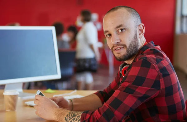 Fiducioso uomo designer sms su un telefono cellulare in rosso spazio ufficio creativo — Foto Stock