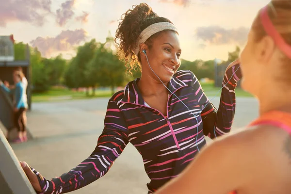 Atleta femenina escuchando auriculares mientras se estira antes de correr al aire libre —  Fotos de Stock