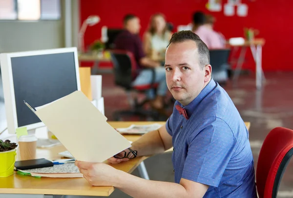 Diseñador masculino seguro sosteniendo una carpeta en el espacio de oficina creativo rojo —  Fotos de Stock