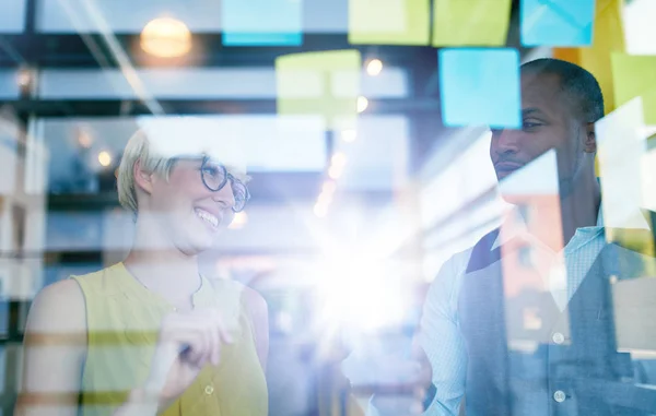 Dos propietarios de pequeñas empresas milenarias creativas que trabajan en una lluvia de ideas de estrategia de redes sociales utilizando notas adhesivas en ventanas — Foto de Stock