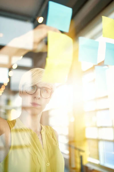 To kreative millenial små virksomhedsejere, der arbejder på sociale medier strategi brainstorming ved hjælp af selvklæbende noter i vinduer - Stock-foto