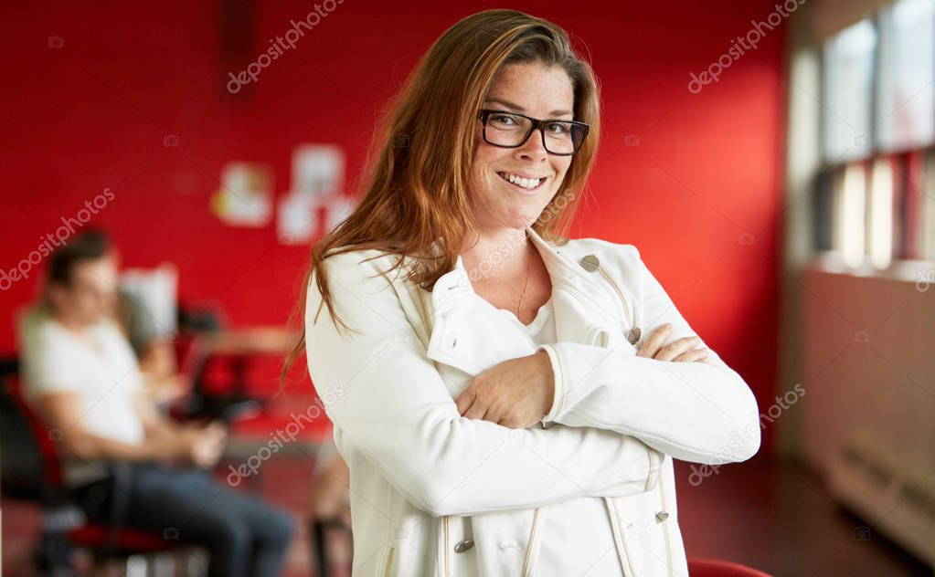 Confident female designer working in red creative office space