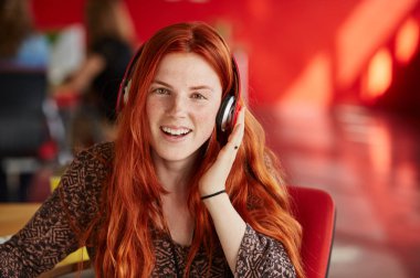 Kendine güvenen kadın Tasarımcısı kırmızı yaratıcı ofis alanı içinde müzik dinlemek