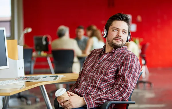 Diseñador masculino seguro escuchando música en el espacio de oficina creativo rojo —  Fotos de Stock