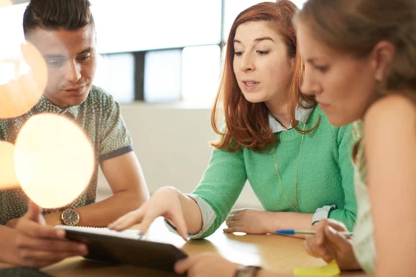 Unposed group of creative business entrepreneurs in an open concept office brainstorming together on a digital tablet. — Stock Photo, Image