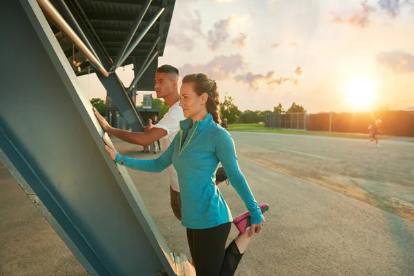 Manliga och kvinnliga idrottare stretching innan kommer jogging utomhus — Stockfoto